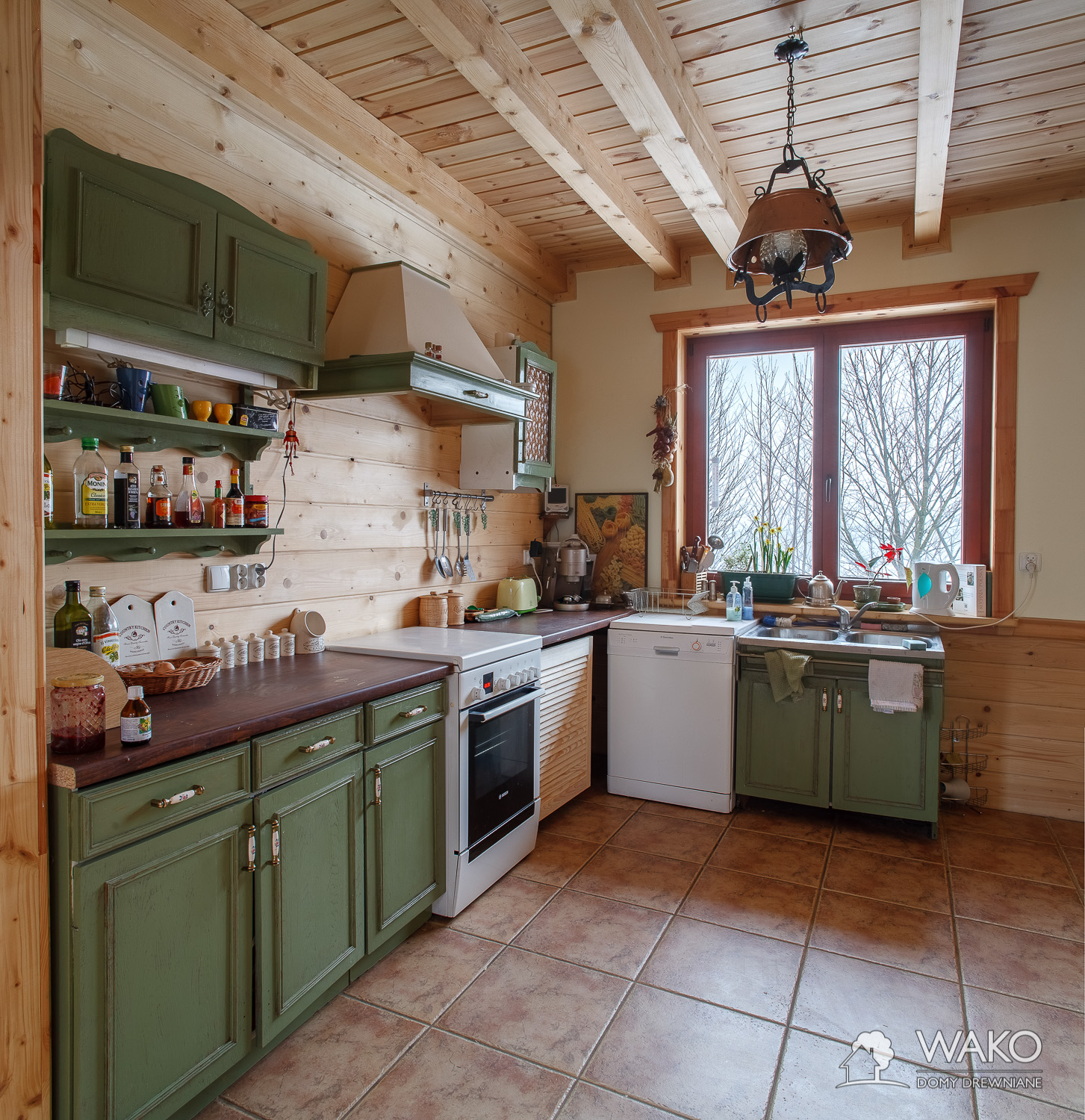 Kuchnia z zieonymi frontami we wnętrzu domu drewnianego
