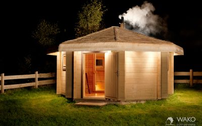 sauna z bali w nocy z dymiącym kominem i iluminacjami